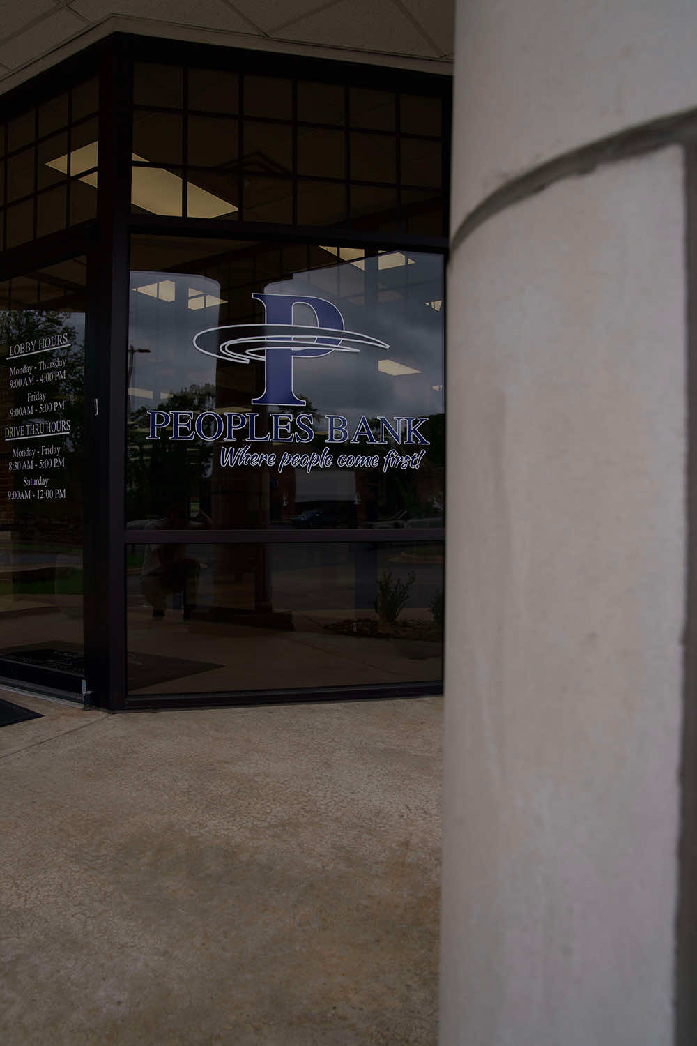 Peoples Bank branch entrance with the bank logo and posted hours on the glass