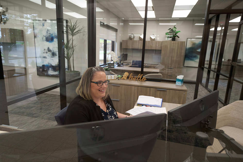 A Peoples Bank employee smiling at her desk while working through paperwork