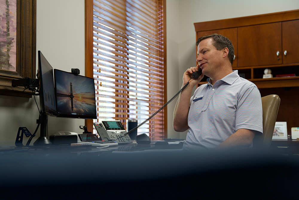 A Peoples Bank banker talking with a customer by phone at his desk