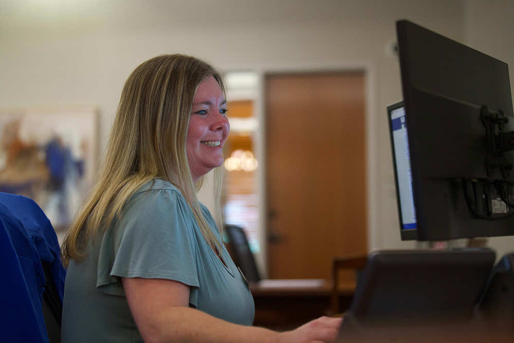A Peoples Bank employee smiling while working at her computer