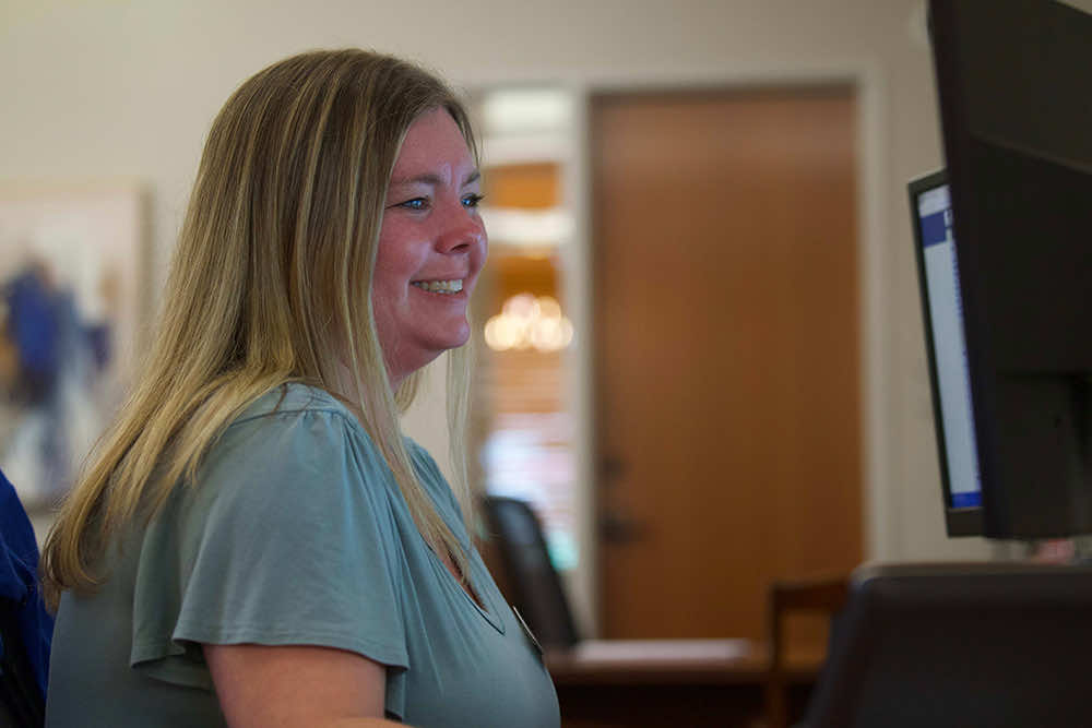 A Peoples Bank employee smiling at a workstation in the branch lobby
