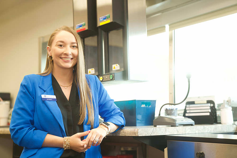 A Peoples Bank teller smiling beside the drive-thru station