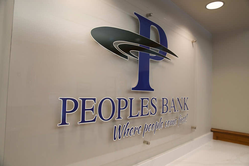 The Peoples Bank logo and "Where people come first!" tagline mounted on a lobby wall