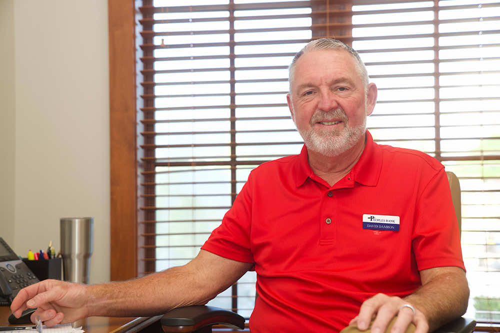 A Peoples Bank vice president smiling at his desk