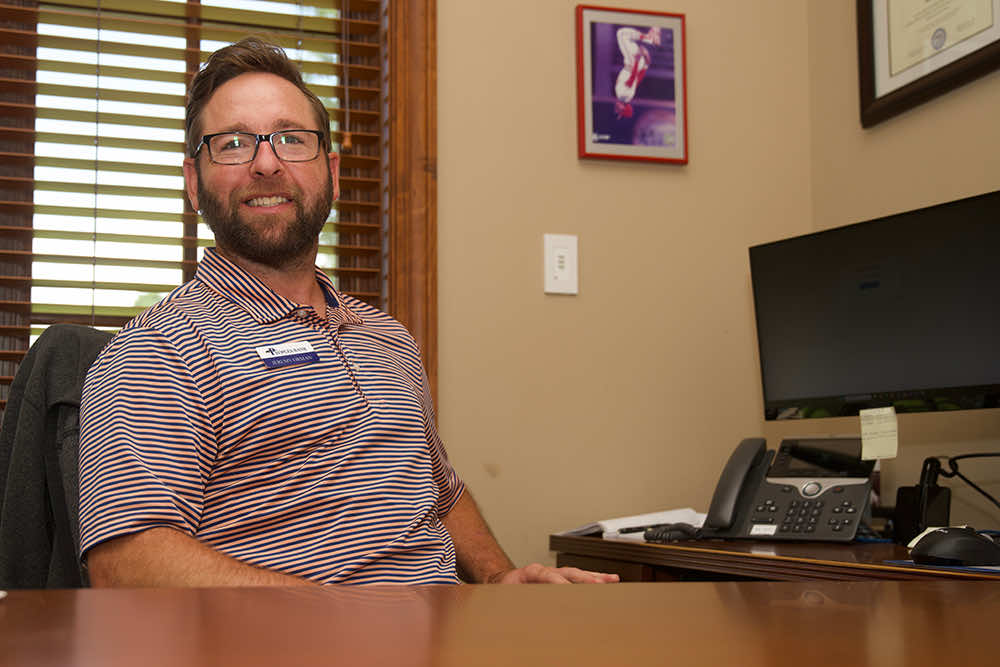 A Peoples Bank banker smiling at an office desk beside a window