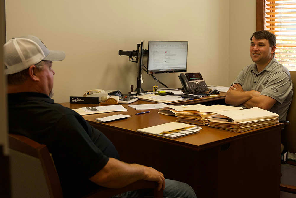 A Peoples Bank loan officer visiting with a customer across the office desk